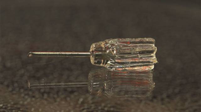 Ein kleiner Schraubendreher mit transparentem Griff liegt auf einer Oberfläche.