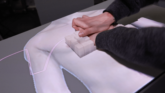 Eine Person drückt mit ihren Händen auf das inForce-Interface, darum ist ein Körper projiziert, so dass es wie eine Herzmassage aussieht.