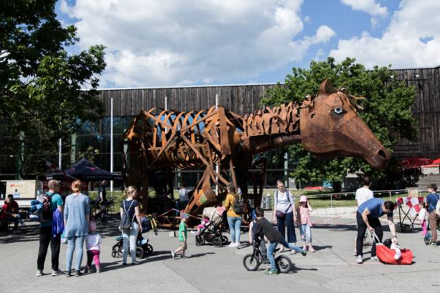 Vor dem FEZ Berlin steht ein mechanisches Pferd aus Metall, um das Elten und Kinder laufen.