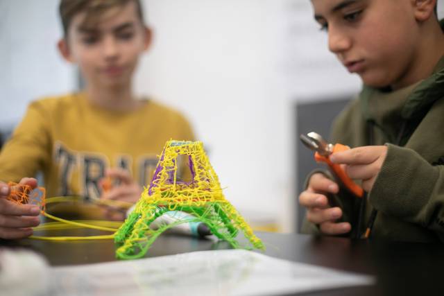 Zwei Jungen bauen einen Eiffelturm mit einem 3D-Druckstift.