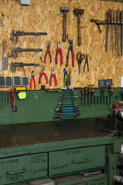 Eine Werkbank mit beschrifteten Schubladen und an der Wand aufgehängtem Werkzeug.