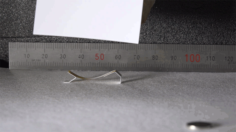 Ein Roboter aus einem Metallstreifen kriecht neben einem Zentimetermaß