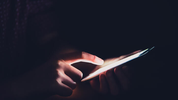 Hände am Smartphone, alles gehüllt in rotes Licht