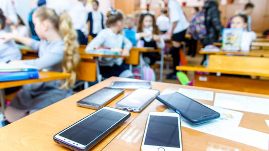Children,Mobile,Phones,Stand,On,A,Teacher's,Desk,In,A