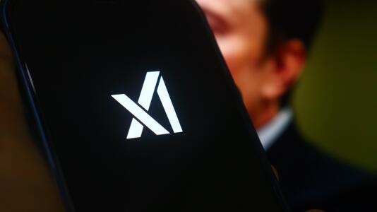 Das Logo von xAI, im Hintergrund die Silhouette von Elon Musk