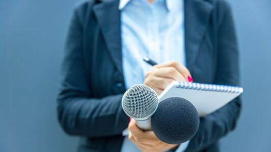 Journalistin mit Notizblock und Mikrophonen