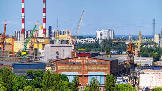 Industrielle Anlage mit Schornsteinen, Kränen und Gebäuden.