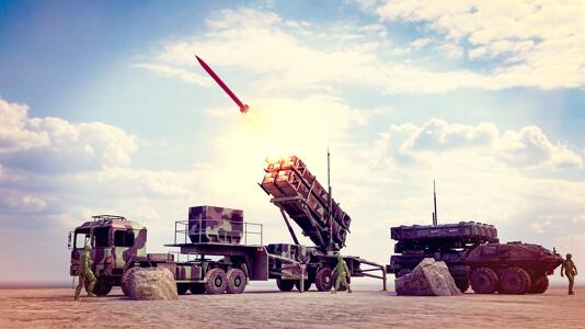 Raketenwerfer feuert eine Rakete ab, Soldaten stehen neben Militärfahrzeugen.
