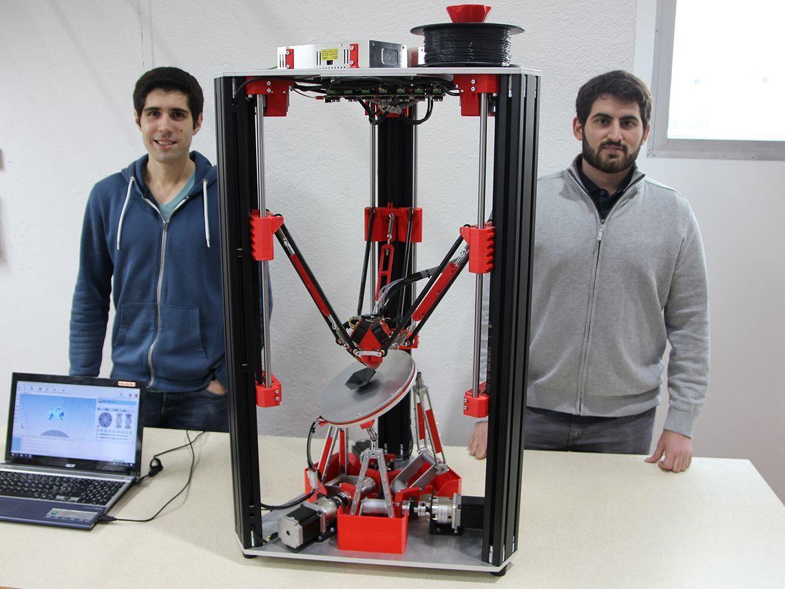 Zwei Studenten stehen neben einem meterhohen 3D-Drucker