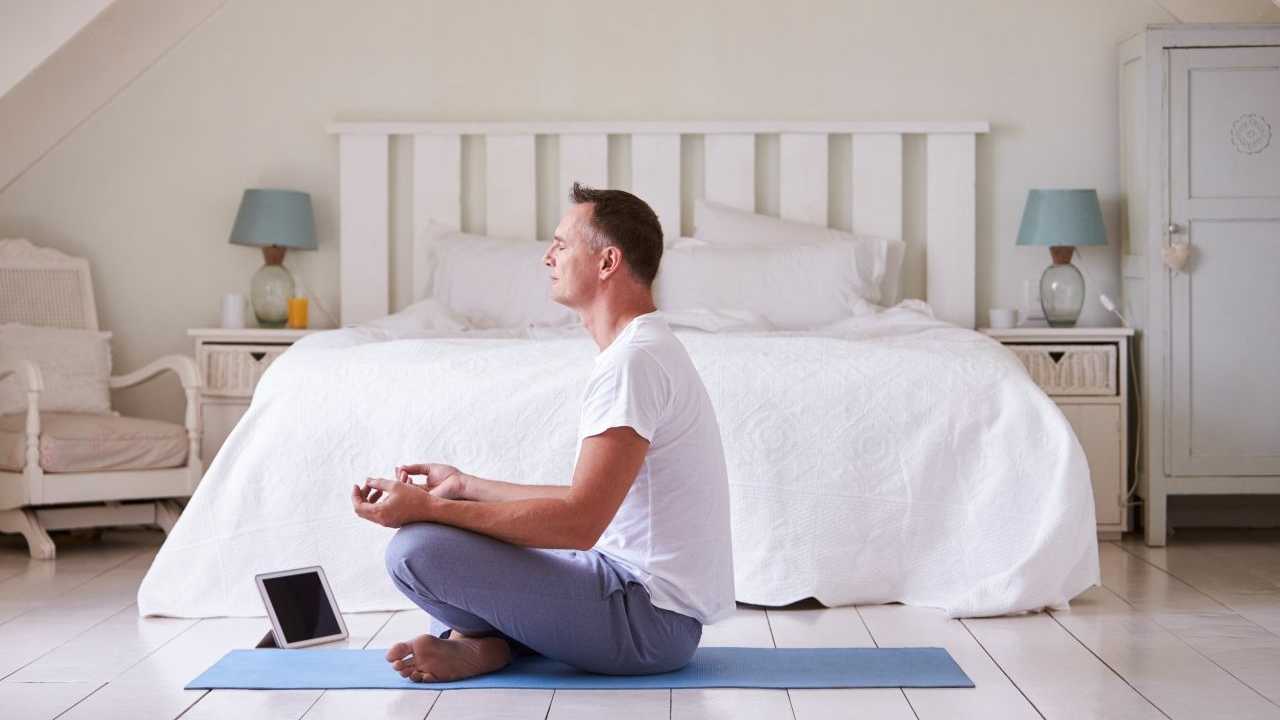 Reifender Mann mit Meditations-App im Schlafzimmer