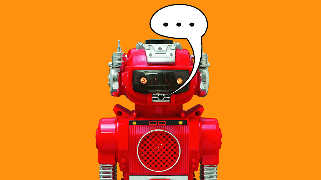 Ein roter Spielzeugroboter von dem eine Sprechblase mit drei Punkten ausgeht.