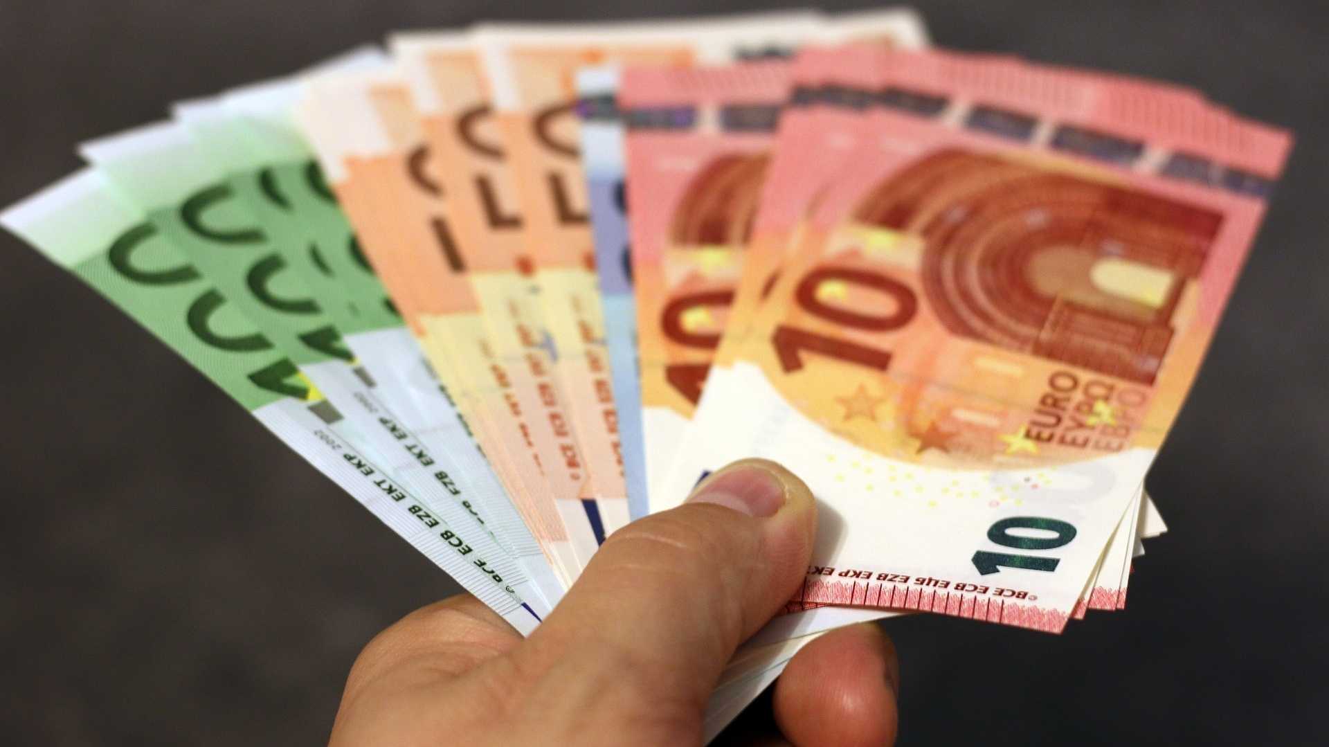 Hand reicht Geldscheine als Symbol für Klimageld bei steigenden CO2-Preisen