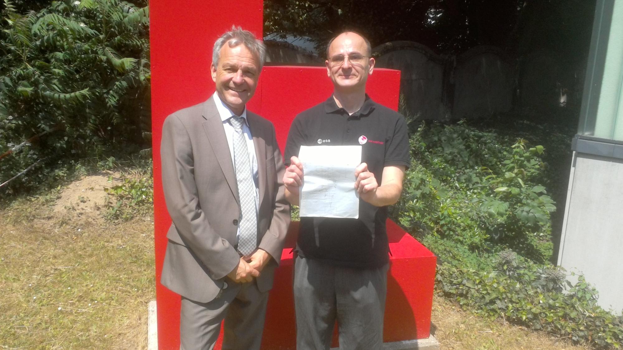 Ein hübsches Gruppenbild im Garten des Albert-Einstein-Instituts in Hannover vor dem "E" für Einstein: Prof . Karsten Danzmann (links) und Prof. Gerhard Heinze, der das originale, handgemalte Lisa-Pathfinder-Konzept mit Testmassen und Interferometer aus dem Jahre 2001 hoch hält.