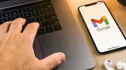 Neben einem Laptop liegen In-Ohr-Kopfhörer sowie ein Handy; es zeigt das Logo für Gmail.
