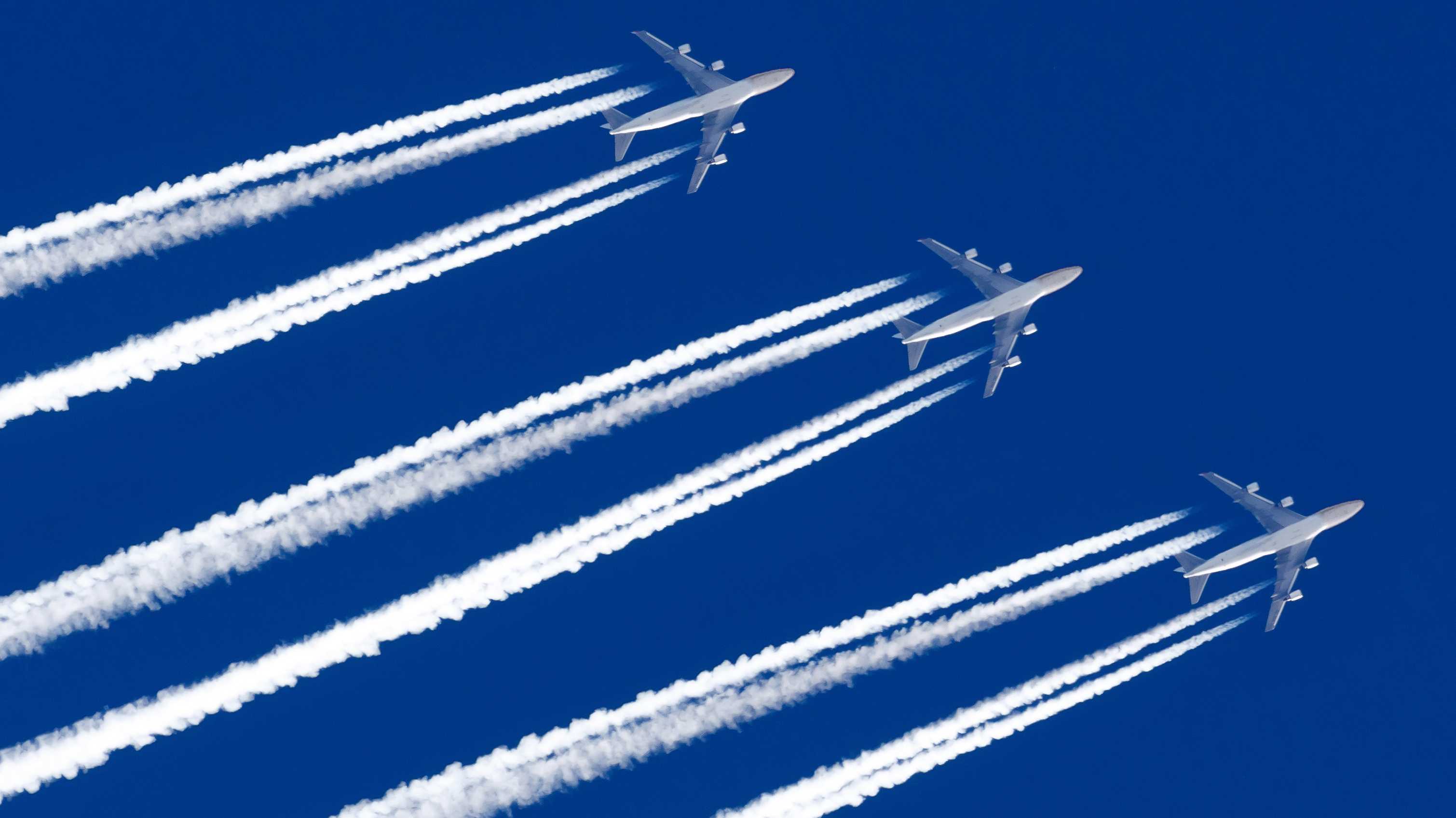 Drei Flugzeuge am Himmel ziehen Kondensstreifen nach.