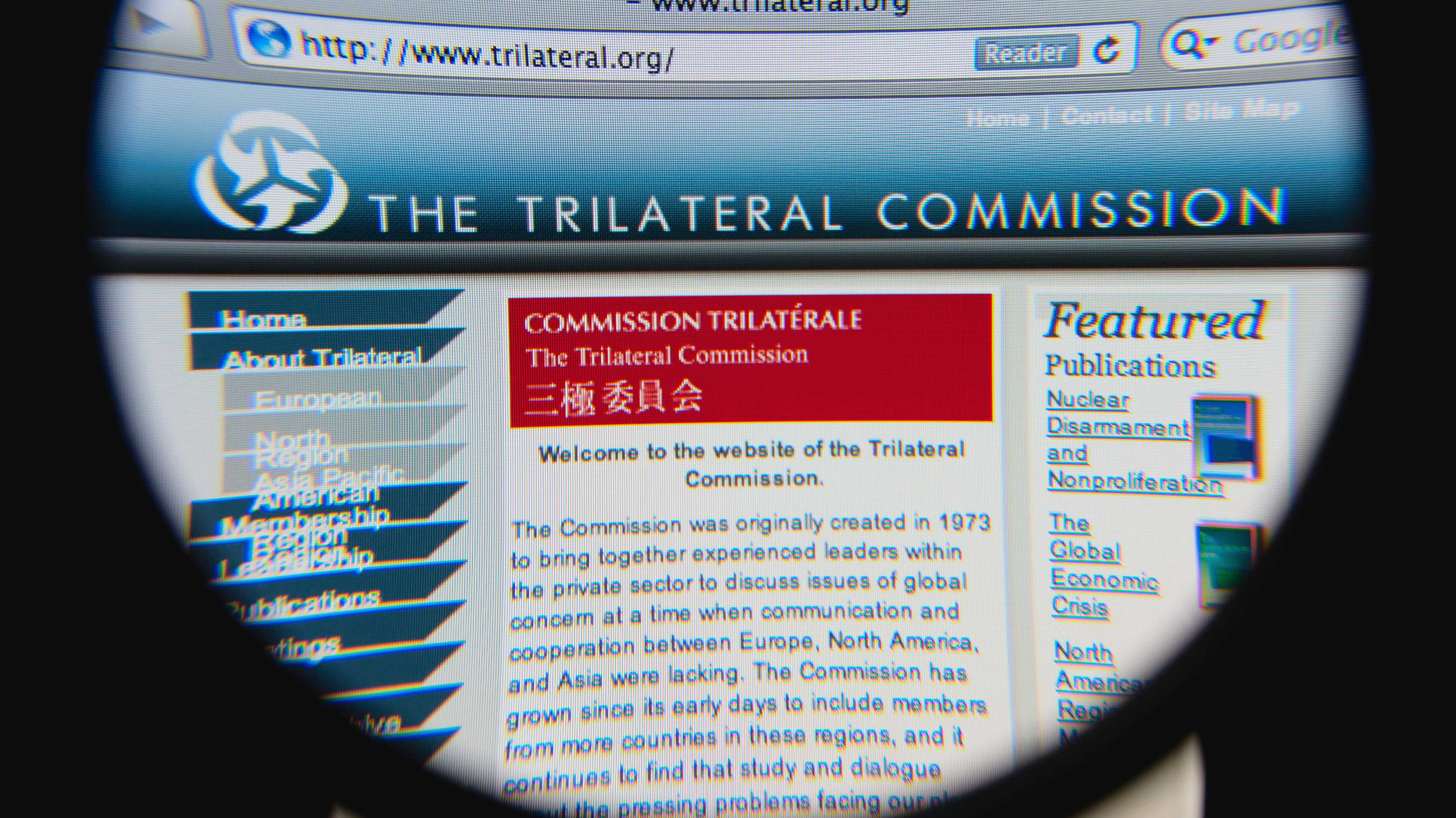 Homepage der Trilateralen Kommission durch eine Lupe