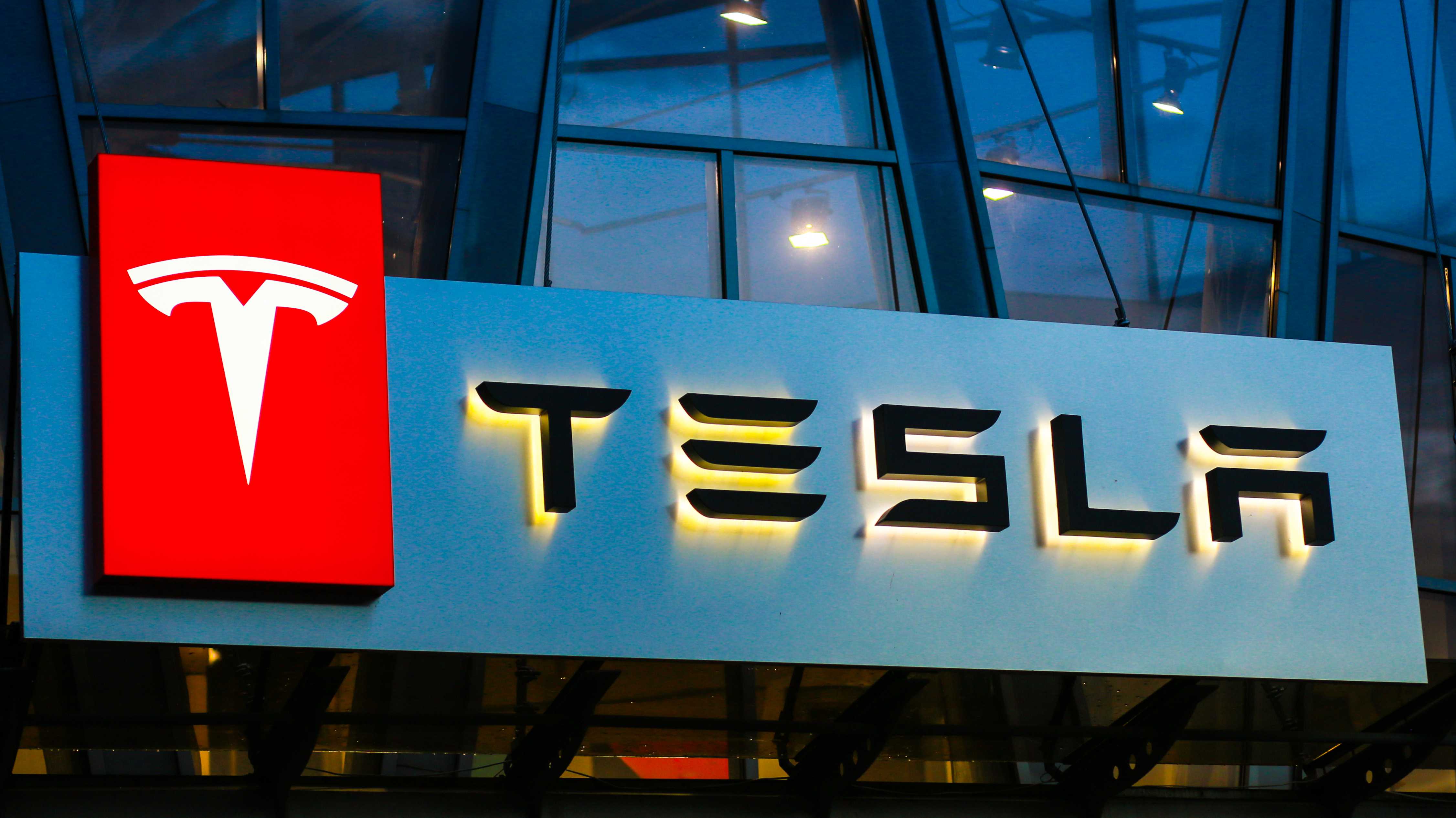 Tesla-Logo auf Gebäude über Autoverkaufsstelle – Symbol der Luxusmarke und ihrer Abkehr von günstigen Elektroauto-Plänen