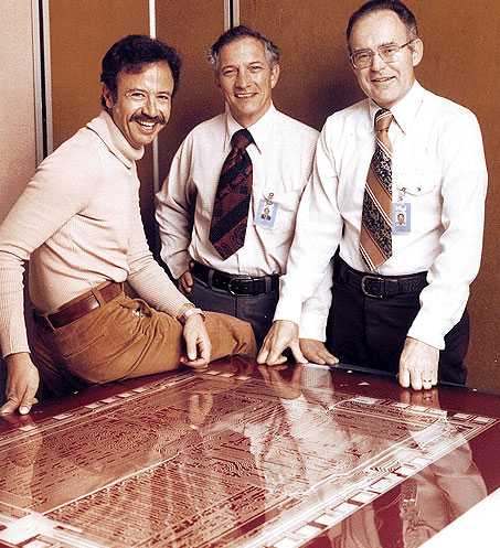 Die Intel Trinity (von links: Andrew Grove, Robert Noyce, Gorden Moore) beim 10-Jahres-Jubiläum vor einem Layer vermutlich des 8080-Prozessors