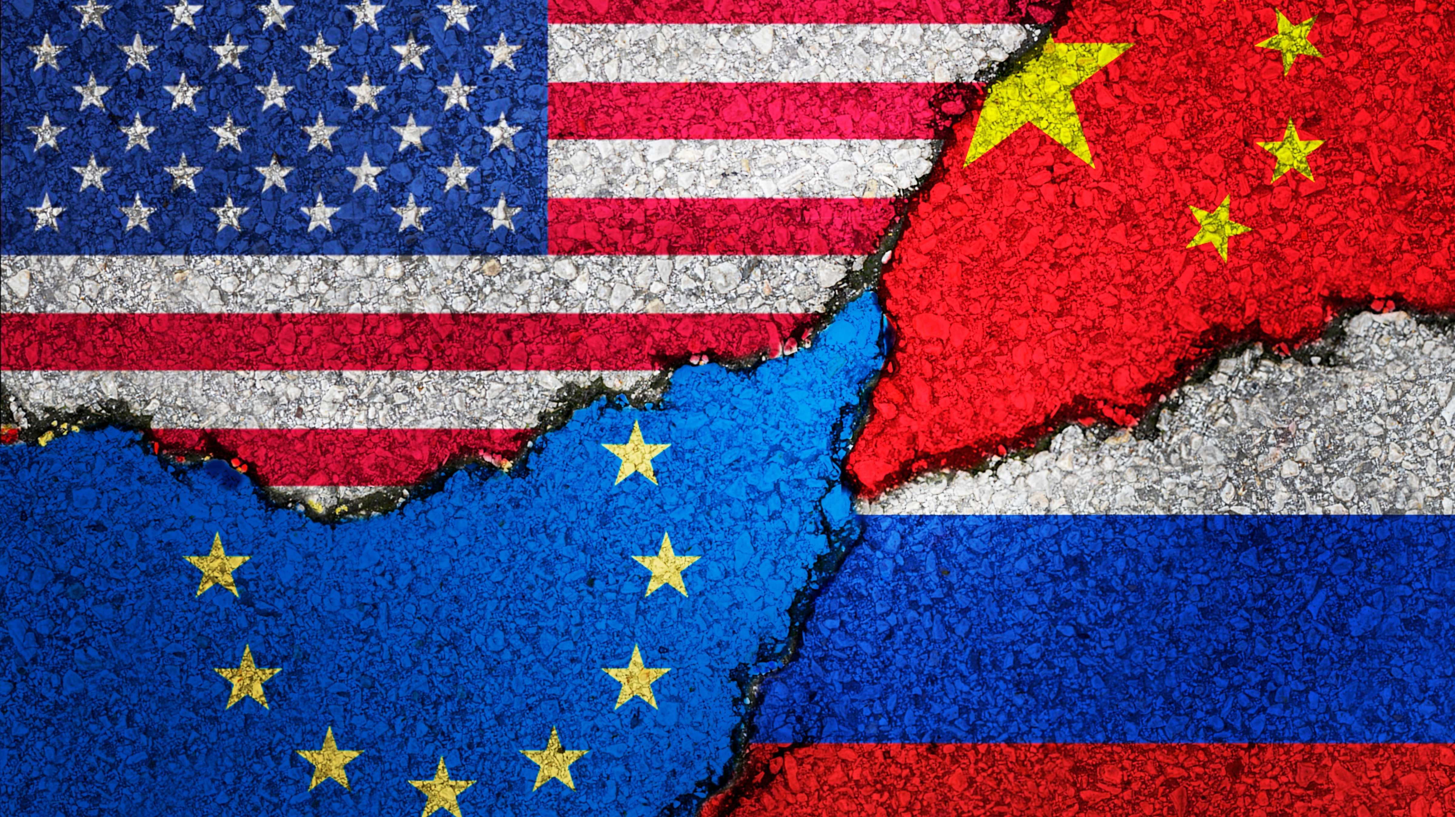 Fahnen von USA, EU, China und Russland sind an eine Wand gesprüht