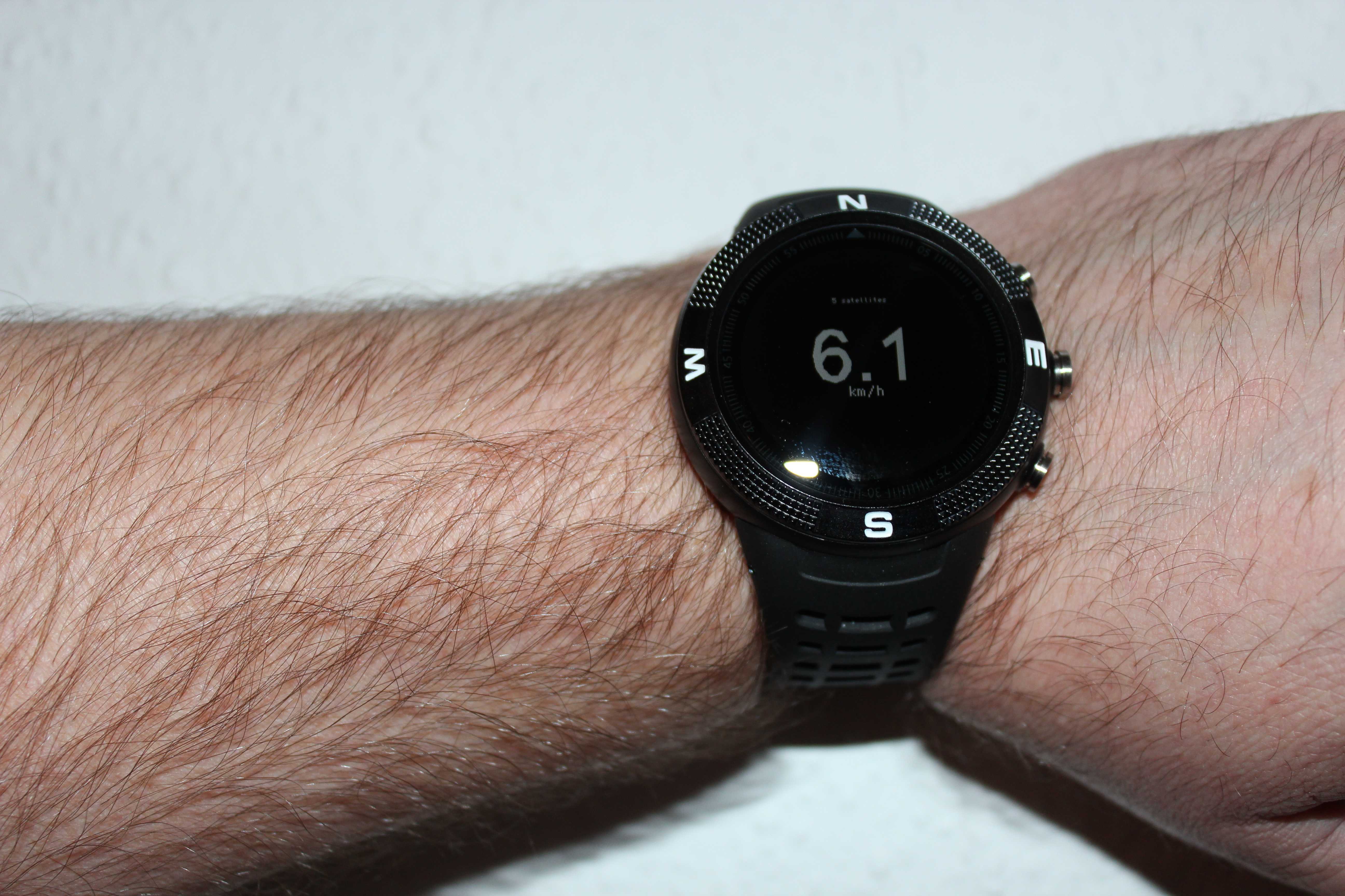 Eine Arm, der eine schwarze Smartwatch am Handgelenk trägt. Auf dem Display steht: 6,1 km/h.