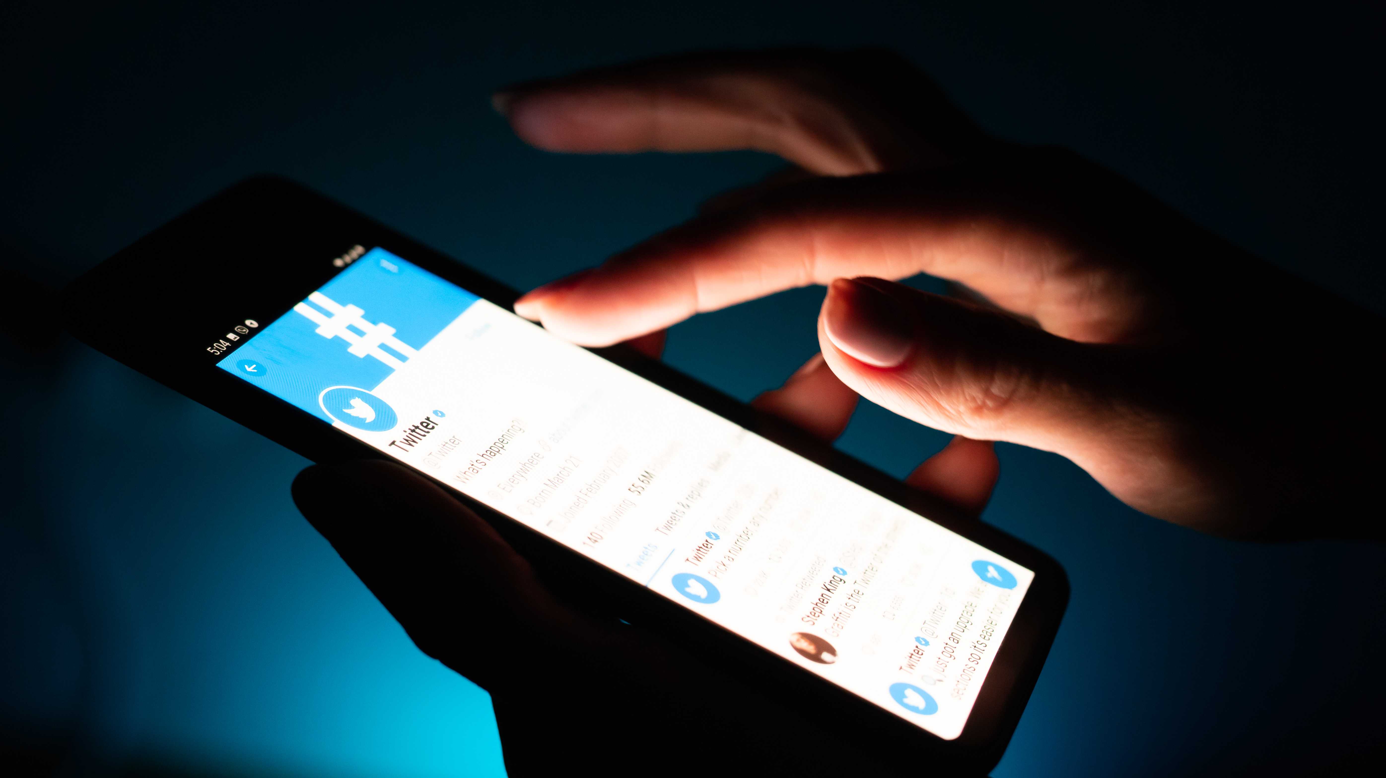 Eine Hand tippt auf ein Smartphone, auf dem die Twitter-App geöffnet ist.