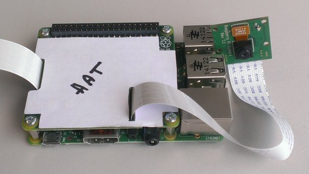 Ein grüner Raspberry Pi auf dem eine Platine befestigt ist. Auf ihr liegt ein weißer Zettel mit der Aufschrift HAT.