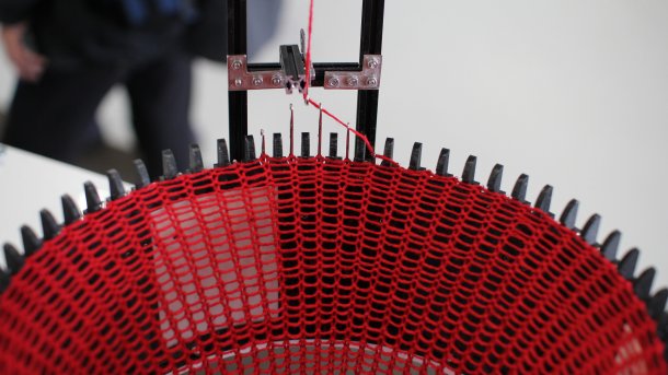 Die Strickmaschine mit rotem Faden in Aktion