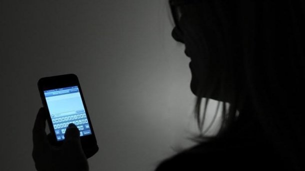 Leuchtendes Handy im Halbdunkel, gehalten von Person 