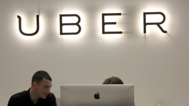 Uber-Schriftzug, darunter 2 Leute an einem Computer