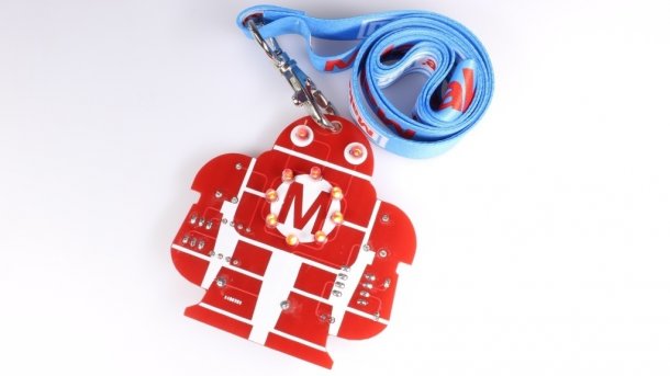 Löt-Makey: Eine rote Platine in Roboterform mit blauem Schlüsselband