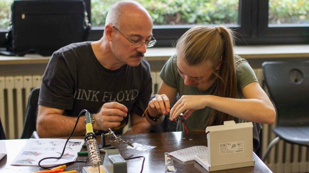 Ein Mann und ein Mädchen beugen sich über ein Elektronikprojekt