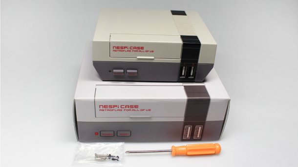 Das NESPi Case, ein grauer Plastikkasten, über einer Pappverpackung im NES-Stil, daneben liegen Schrauben und ein Schraubendreher