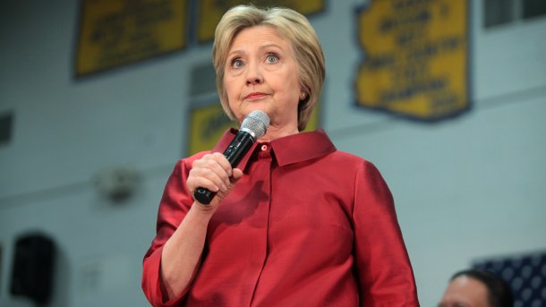 Hillary Clinton in rotem Anzug mit Mikrofon