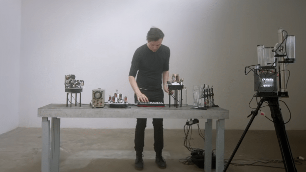 Moritz Simon Geist hinter einem Tisch mit Musikrobotern