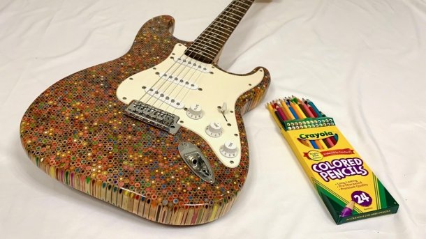 Gitarre mit Körper aus Buntstiften neben einer Buntstiftpackung