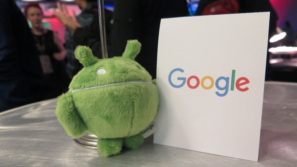 Grüner Plüsch-Androide neben Schild "Google"