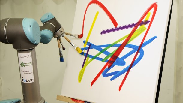 Ein Roboterarm hält vier Pinsel mit Farbe vor einer Leinwand.