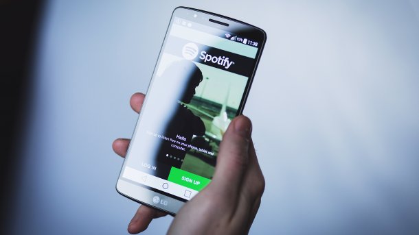 Hand hält Handy mit aktiver Spotify-App