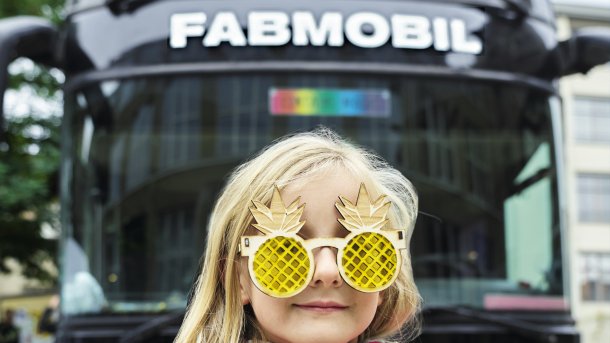 Ein Kind mit gelaserter Scherz-Brille vor dem Fabmobil.