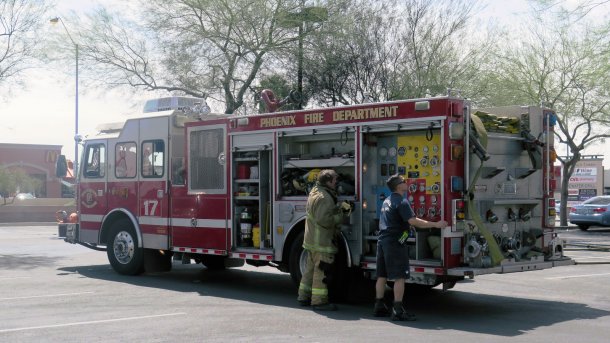 Löschfahrzeug der Feuerwehr Phoenix', davor zwei Feuerwehrmänner