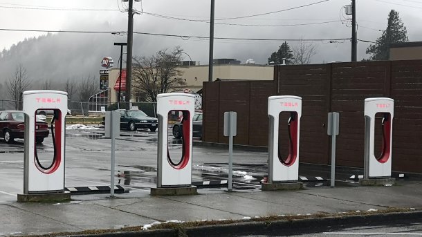 4 ungenutzte Tesla-Ladestationen, dahinter ein Parkplatz