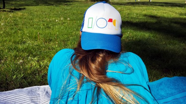 Rückensicht einer blonden Frau, die eine Google-I/O-2019-Kappe tragend im Gras liegt 