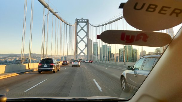 Blick durch die Windschutzscheibe auf die Bay Bridge Richtung San Francisco, zu sehen sind auch Aufkleber "Uber" und "Lyft"