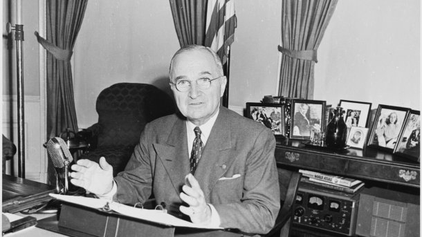 Harry S. Truman an Schreibtisch sitzend