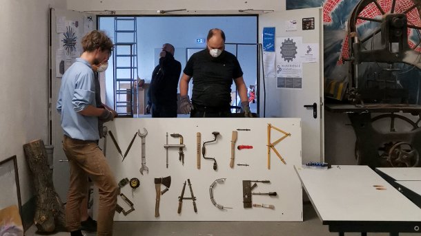 In einer Tür stehen vier Menschen um ein Schild mit der Aufschrift "Makerspace".