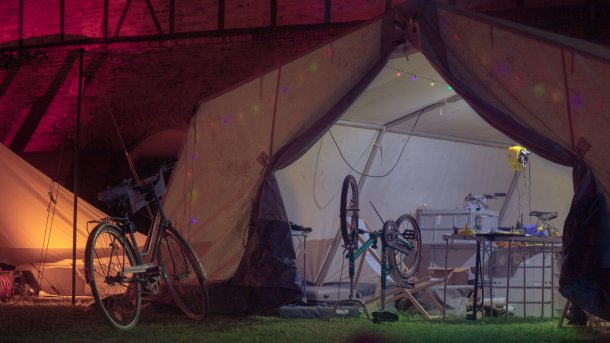 In einem großen, beleuchteten Zelt steht ein umgedrehtes Fahrrad.