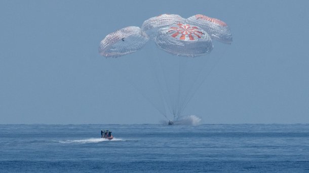 Kapsel mit 4 Fallschirmen knapp über dem Meer