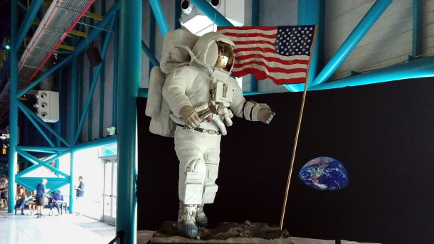 Lebensgroße Figur in Astronautenanzug, daneben eine US-Flagge