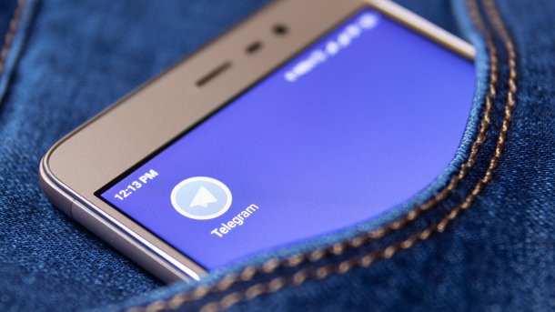 Handy mit Telegram-Icon lugt aus Jeanstasche hervor