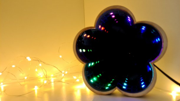 Ein Spiegel in Form einer fünfblättrigen Blume, in dem bunte LEDs in die Unendlichkeit gespiegelt werden.